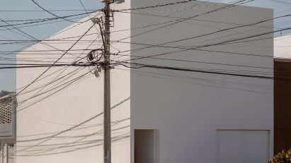 A white cube house on a street corner with telephone poles