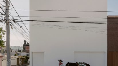 Exterior of a white cube house by HW Studio Arquitectos with a man, horse and dog out front