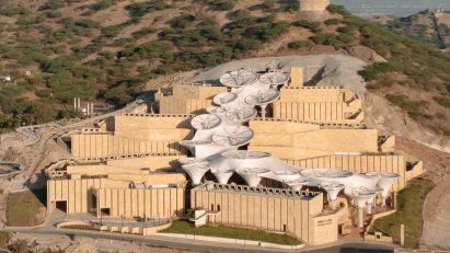 Exterior of the Smritivan Earthquake Memorial Museum by Vastushilpa Constultants with stone walls zigzagging up a sloped site