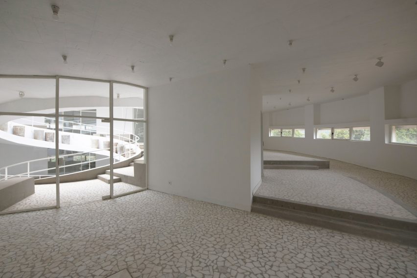 White interior room with glazed walls overlooking a spiral staircase