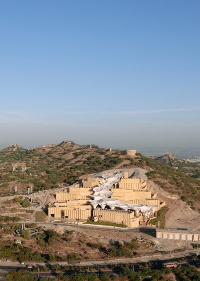 Exterior of the Smritivan Earthquake Memorial Museum by Vastushilpa Constultants with stone walls zigzagging up a sloped site