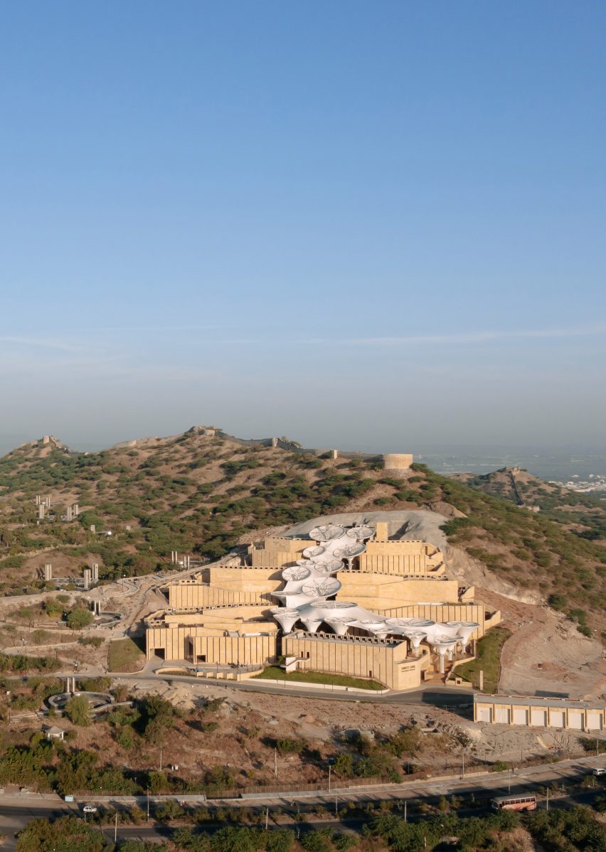 Exterior of the Smritivan Earthquake Memorial Museum by Vastushilpa Constultants with stone walls zigzagging up a sloped site