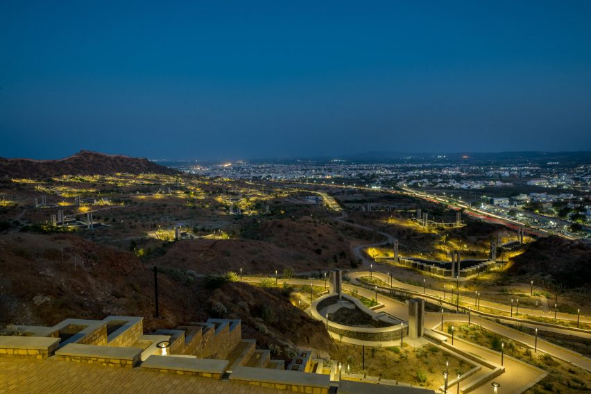 A hilly landscape at night with a fort wall lit up