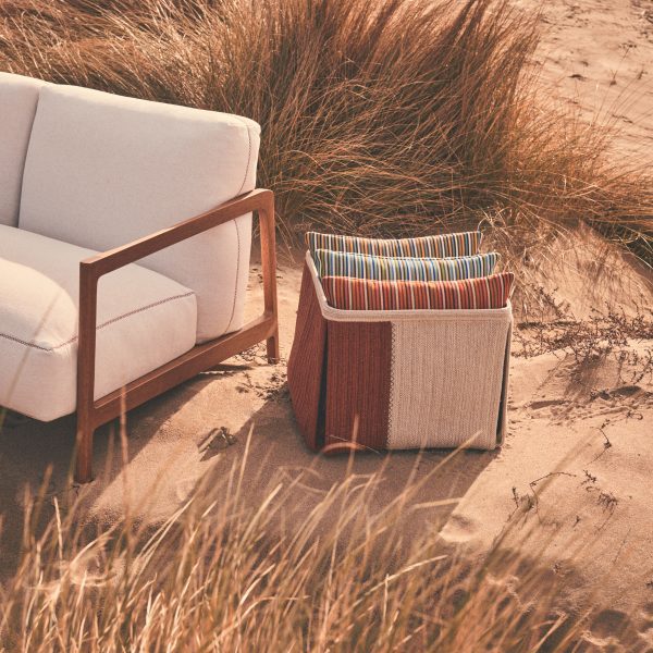 Cushions stacked next to white sofa on beach
