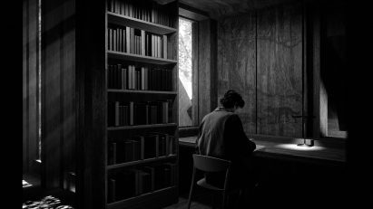 Black and white image of someone sitting at a desk