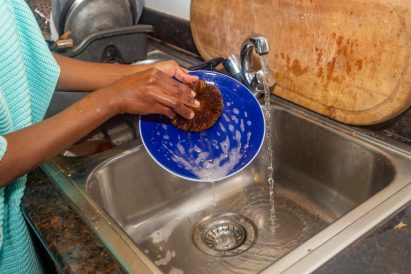 Person washing a plate with an EcoCoCo scrubbe from Afri-Plastics Challenge