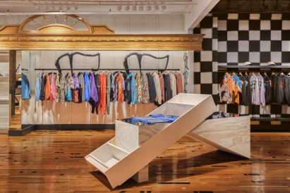 Clothing hung on rails below a carved wooden frame