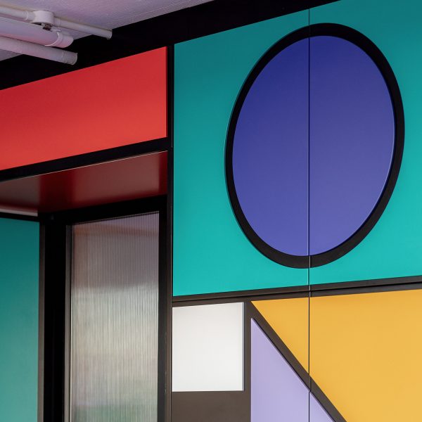 Close-up photo of colourful cabinetry at Camille Walala's studio showing relief pattern of cut-out shapes glued onto black MDF doors