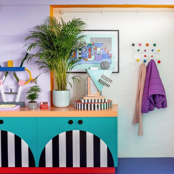 Photo of details in a colourful office space with bold cabinetry, bright blue floors and plants and colourful ornaments on display