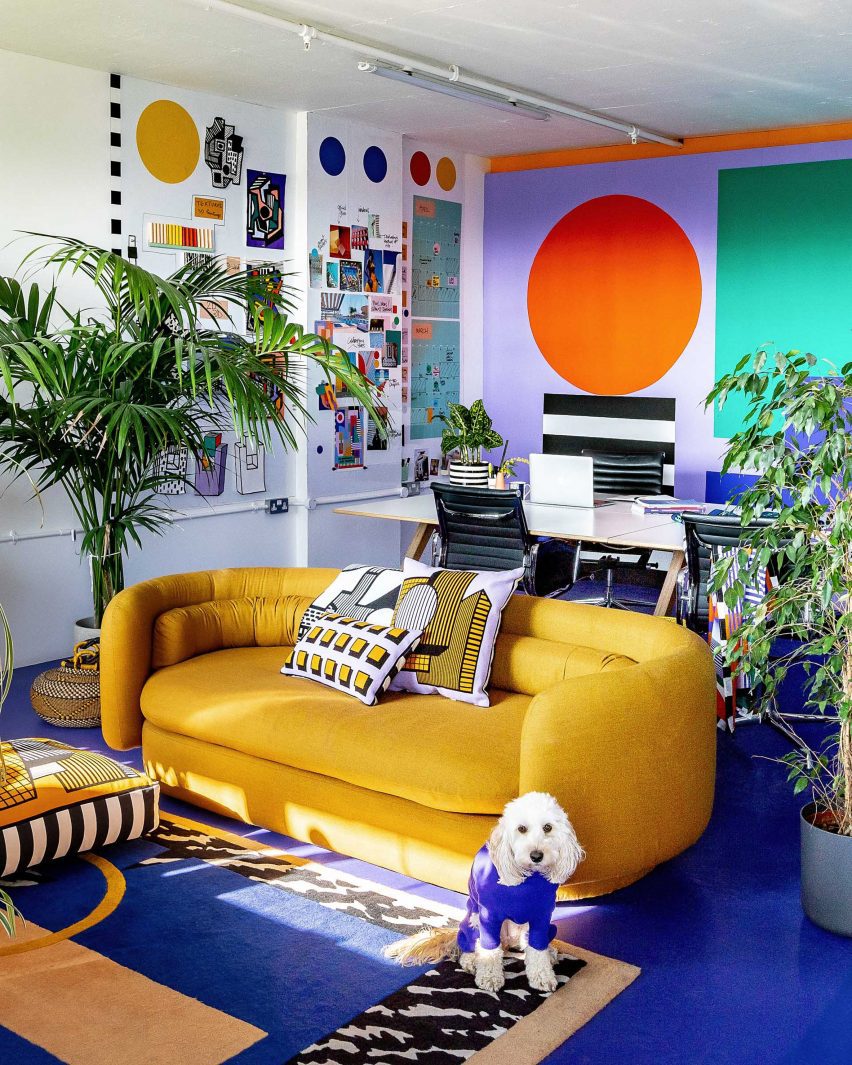 Photo of a colourful office space with a yellow sofa in front of a big worktable