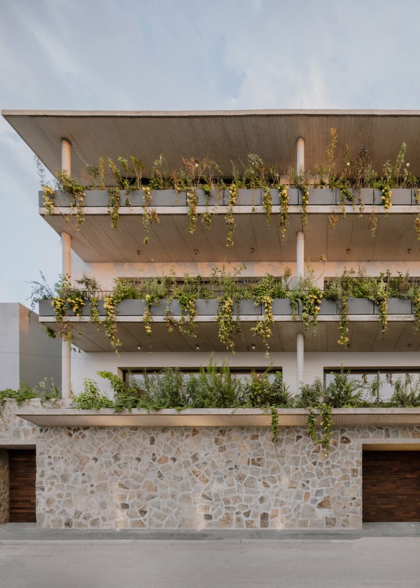 Four-storey apartment building with stone walls and planted balconies