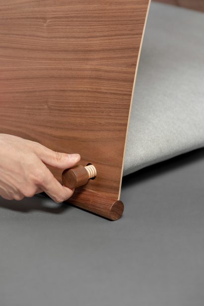 Hand tightening wooden screw on side of dog bed