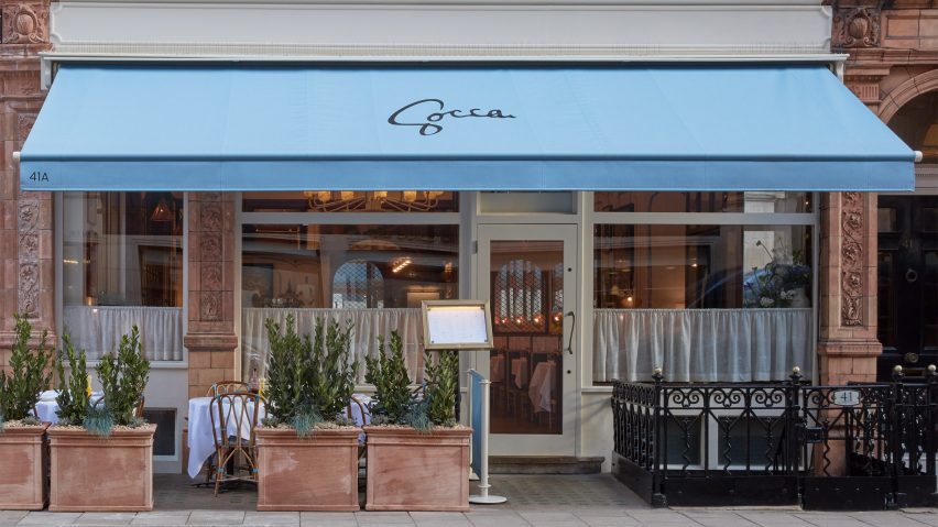 Exterior of the Socca restaurant in London with terracotta walls and a blue canopy