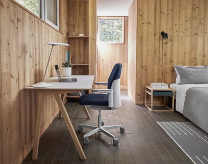 Blue upholstered Path office chair by Humanscale in a timber-clad interior at a wooden desk