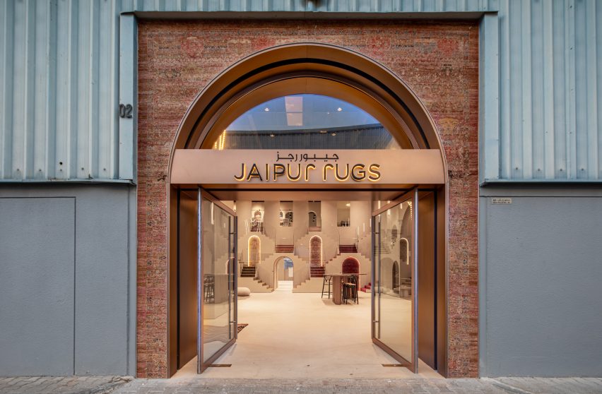 Photo of the outside of Jaipur Rugs Dubai showroom showing a brick entrance with rose gold signage built into a warehouse