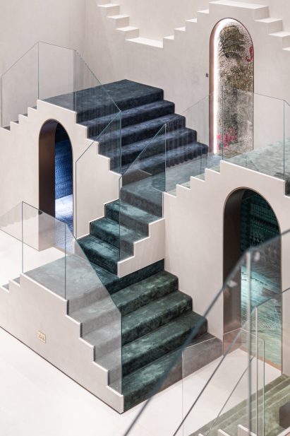 Photo of staggered staircases in Dubai showroom covered with carpet in a gradient of indigo and emerald tones over two arched doorways