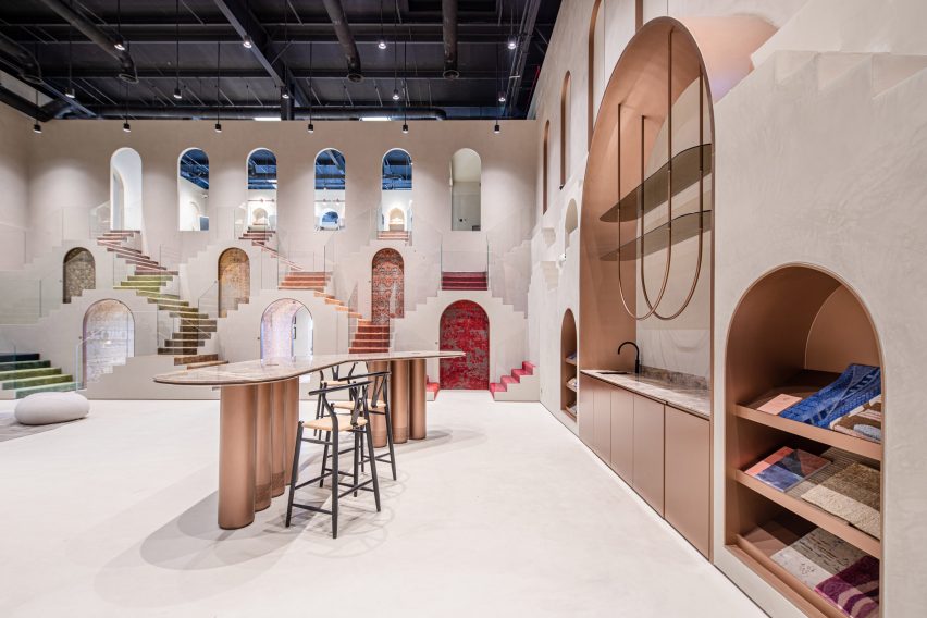 Photo of the double-height showroom for Jaipur Rugs in Dubai showing metallic rose pink details in the furniture, doorways, recesses and cabinetry