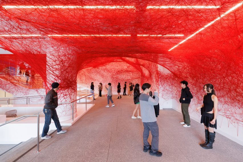 Museum gallery space with white walls covered in red threads
