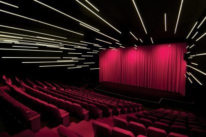Theatre space with black walls and ceilings, strip lighting and hot pink seats