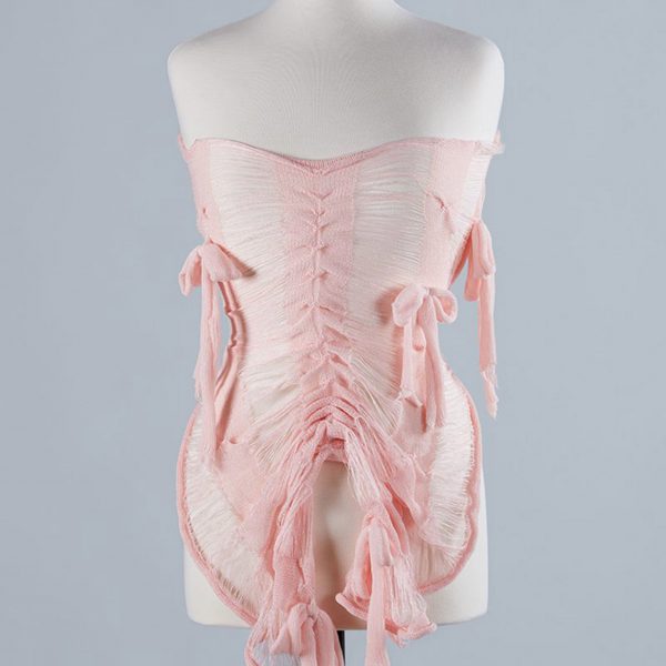 Photograph of pink lace corset with bows on white mannequin in front of grey backdrop