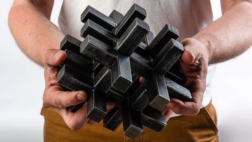 Person holding a black sculpture made up of interlocking 3D crosses by a New Designers winner