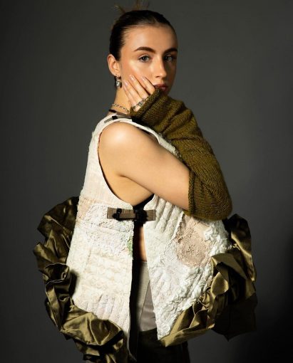 Model wearing lacy top and gloves on black backdrop