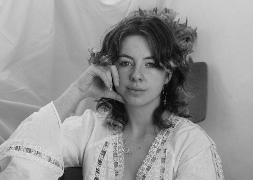 Black and white photo of designer Mary Holmes with wavy mid-length hair and a white emboidered shirt