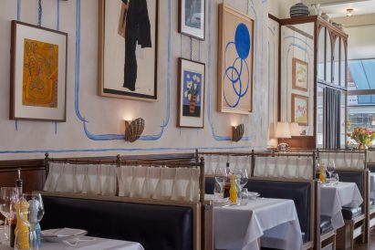 Socca restaurant interior with booth seating and blue wall murals informed by France
