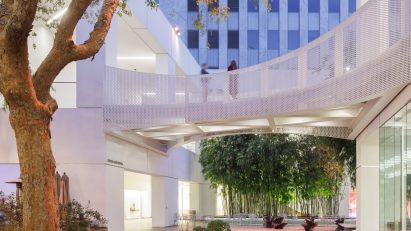 Courtyard at the Hammer Museum with a tree, outdoor seating and white buildings connected by a bridge