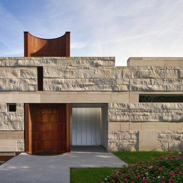 Exterior of a rocky-clad wall with an opening revealing a half-tubular orange tower