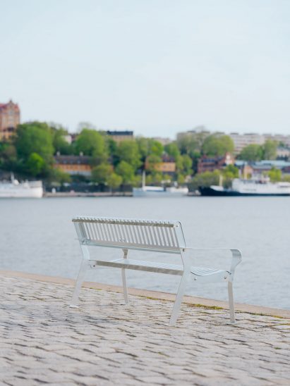 Photo of the Tellus bench by Vestre on a sandy shoreline overlooking the water