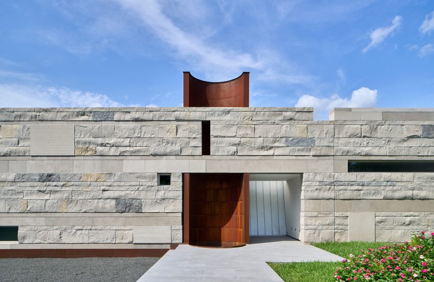 Exterior of a rocky-clad wall with an opening revealing a half-tubular orange tower
