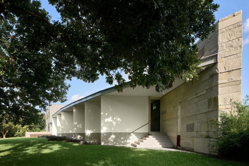 Exterior of a home with a large stone wall and white separating walls in a garden