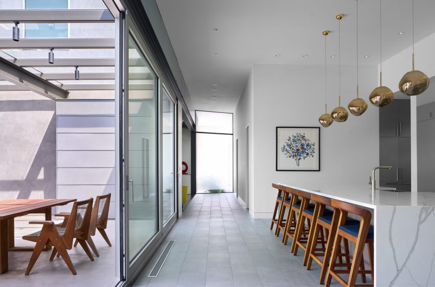 Kitchen with sliding glass doors, porcelain floor tiles and a white marble kitchen island