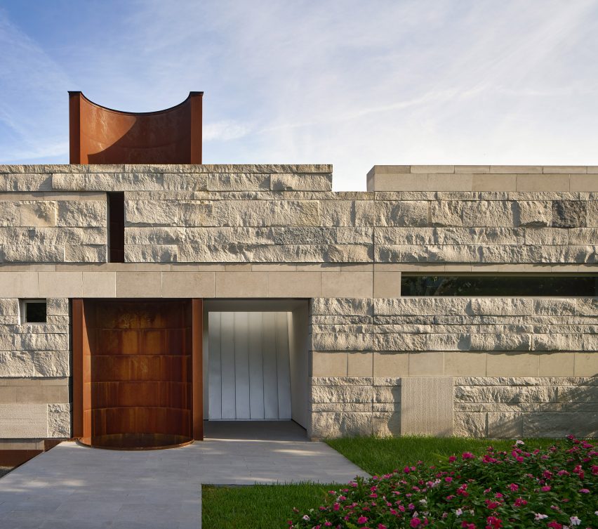Exterior of a rocky-clad wall with an opening revealing a half-tubular orange tower