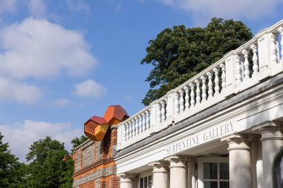Photo of the outside of the Serpentine South building with a small, birdhouse-like Tomás Saraceno Cloud Cities sculpture sitting on the facade