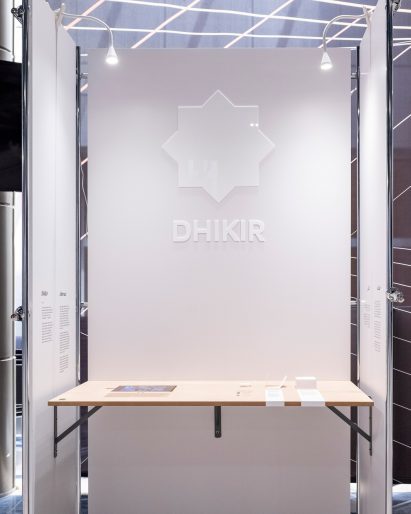 A white-walled booth with a wooden shelf as part of a student exhibition by Virginia Commonwealth University