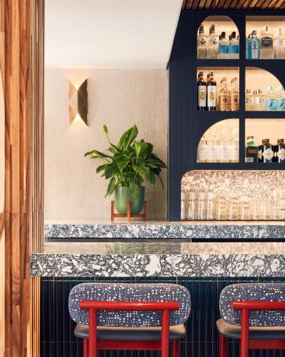Detail of a stone bar counter with red-framed stools