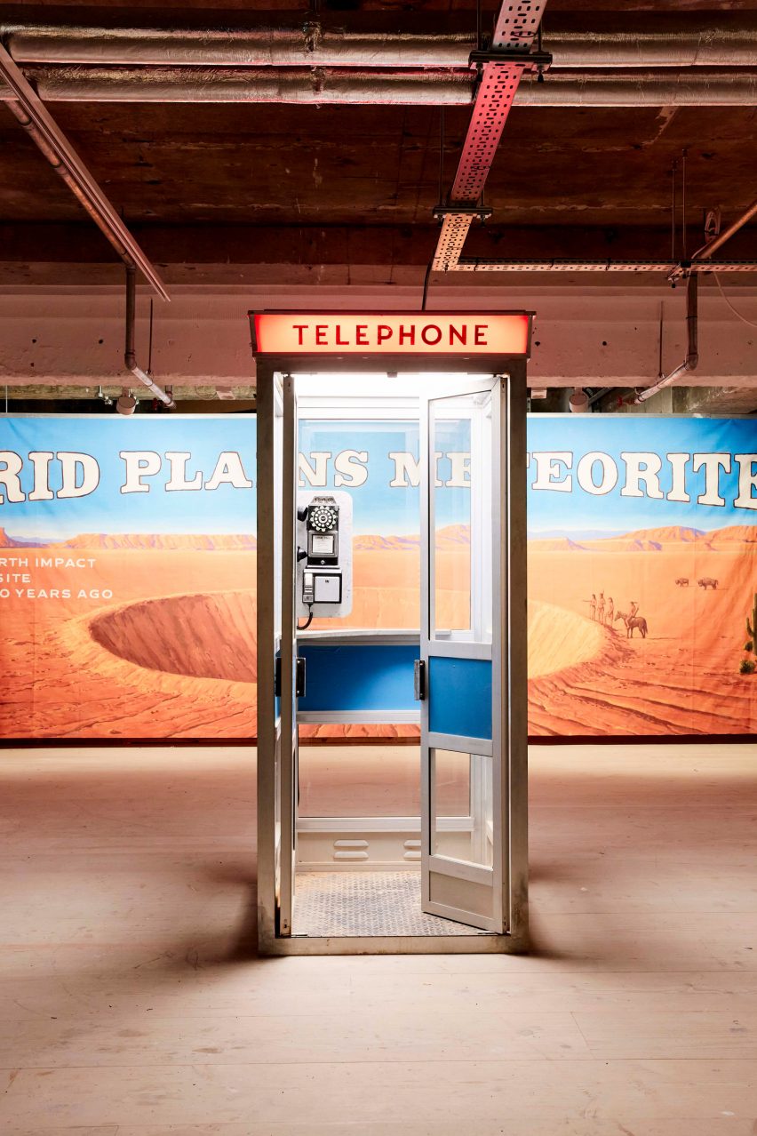 A telephone booth in front of a meteor crater billboard poster