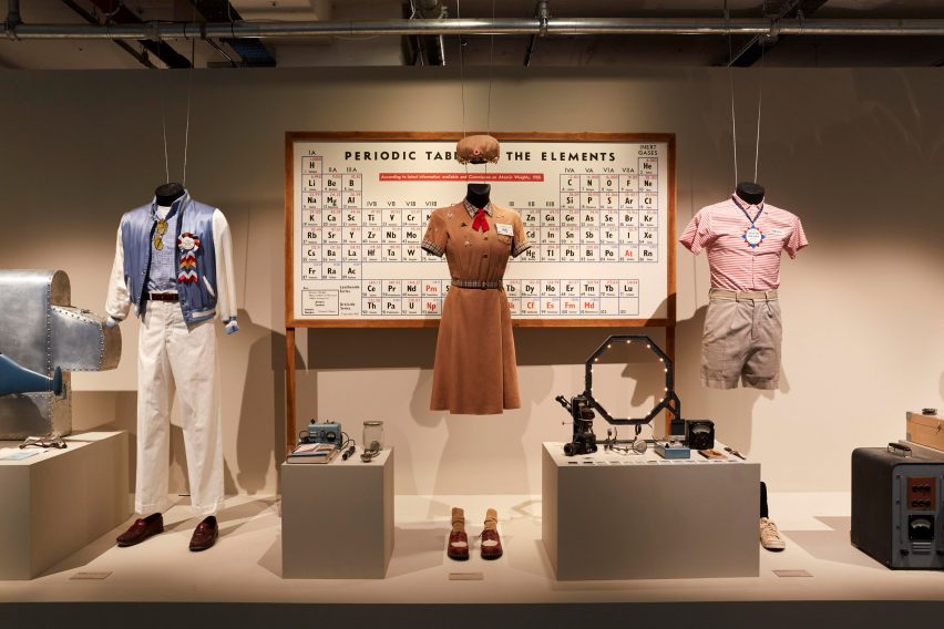 Three film costumes in front of a periodic chemistry table