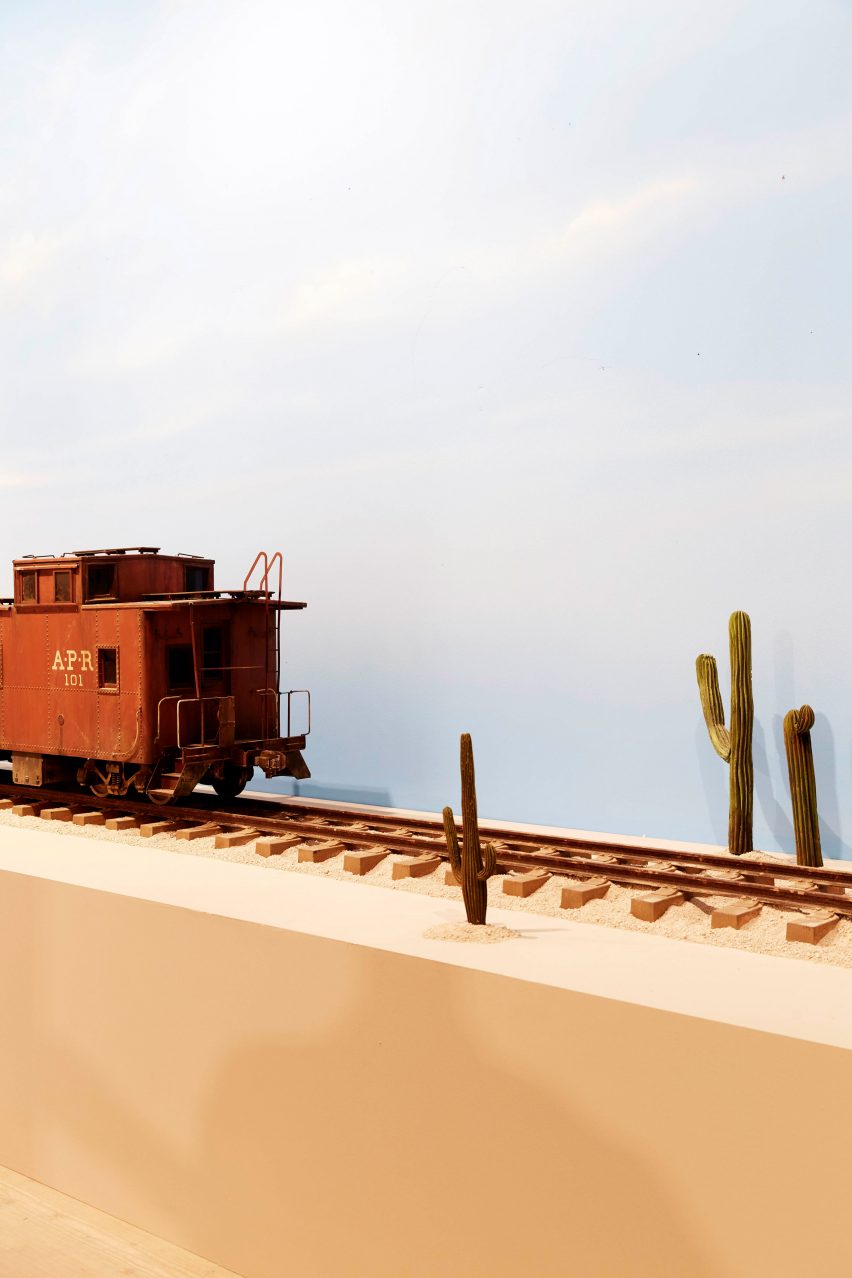 A model train on a rail track with cacti