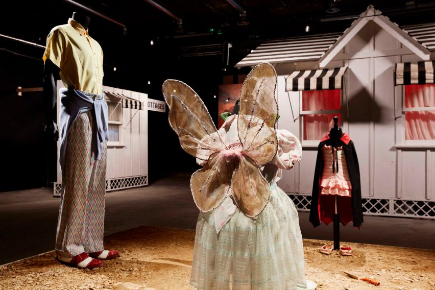 Three costumes arranged around a patch of desert for the Asteroid City exhibition