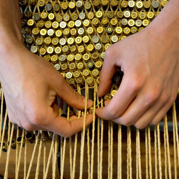Photo of hands weaving bullet shells
