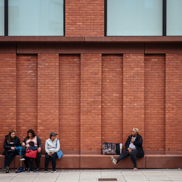 Photo of people sat by a brick wall