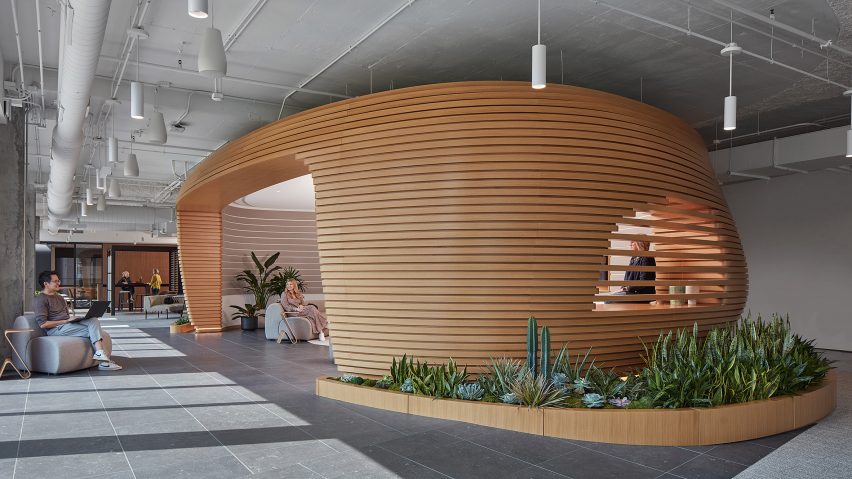 Curved timber workspace within a grey office interior