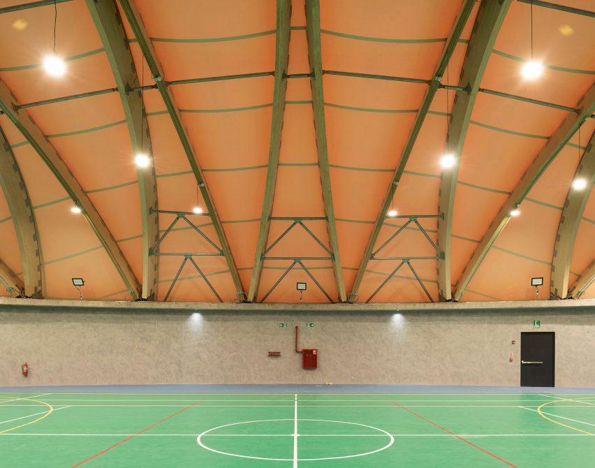 A sports facility with wooden arches and a bright green court