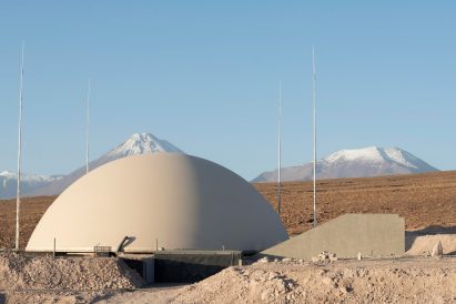 A curved building with mountains in the back