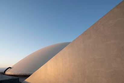 A concrete wall in front of a curved underground building