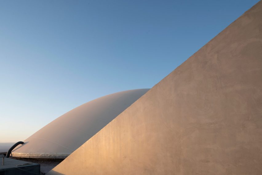 A concrete wall in front of a curved underground building