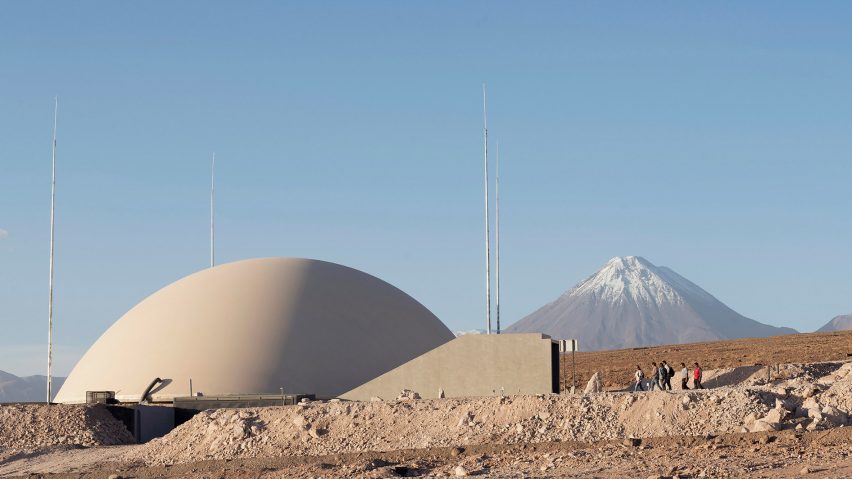 People walking into a curved building in the desert